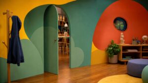 A realistic editorial image of a colorful animation studio-style set with a playful concealed entrance in a painted wall.