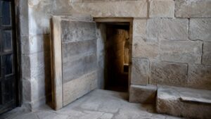 A realistic old stone interior with a partly opened concealed entrance and no readable markings.